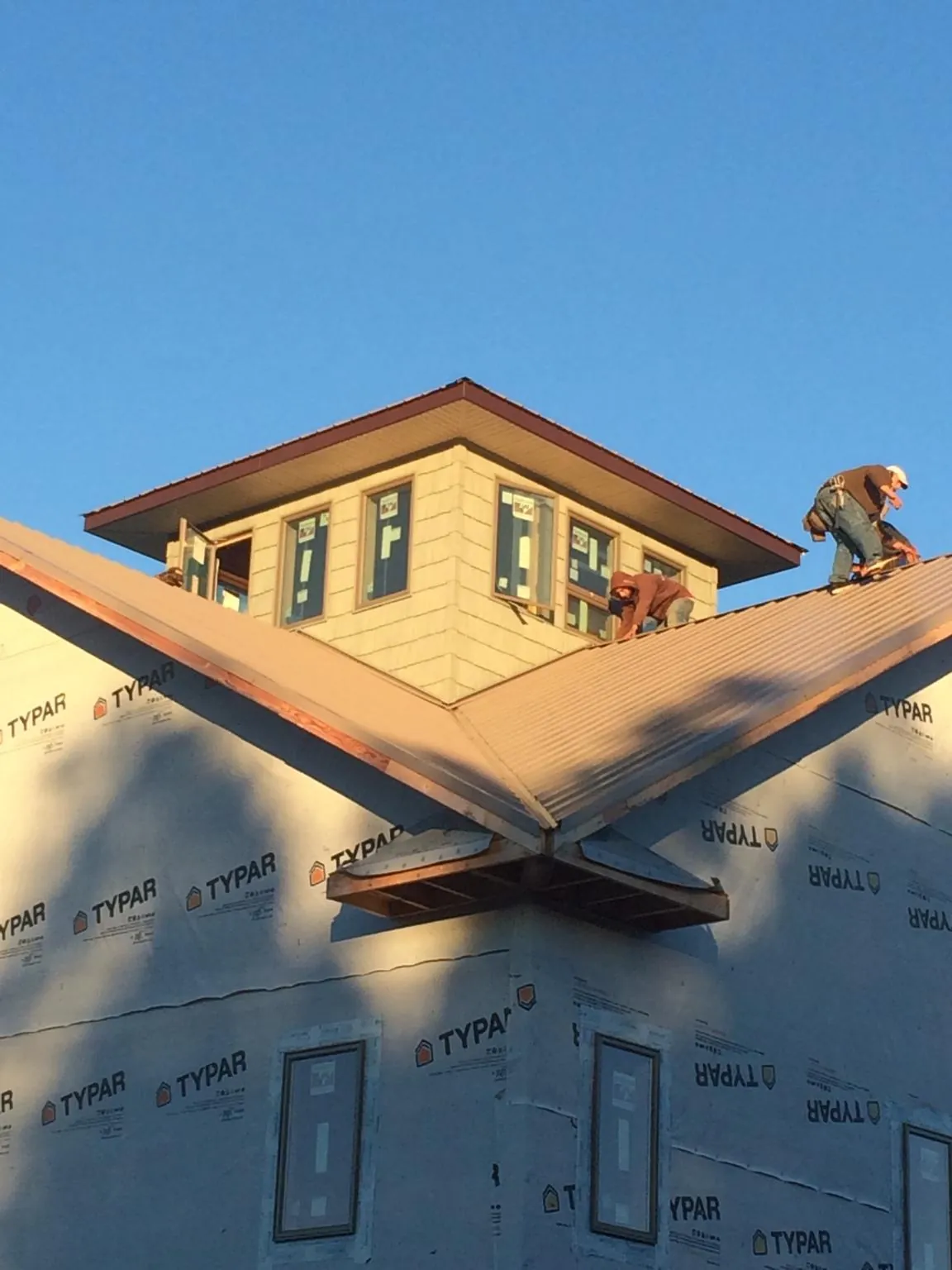 Roofers working around a rooftop cupola on a new metal roof at sunset — Roof Waterproofing in Diamondhead by Roofing Brothers